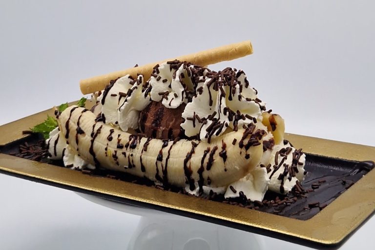 Bananensplit Banane mit Schlagsahne, Schokolade und einem Waffelstäbchen dekoriert.