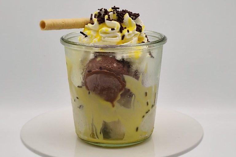 Eierlikörbecher Ein Glas mit Schokoladeneis, Sahne, Schokoladensoße, Eierlikör und einem Waffelröllchen.