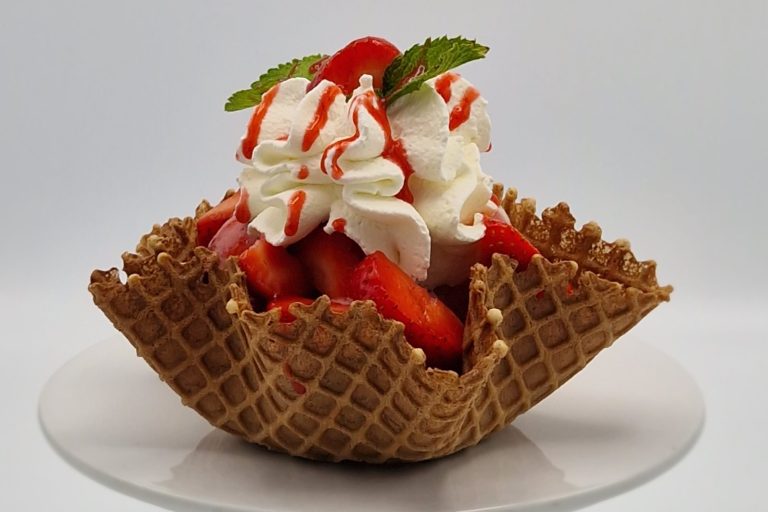 Erbeerbecher Eiswaffelschale mit Erdbeeren, Schlagsahne und rotem Sirup, garniert mit Minze.