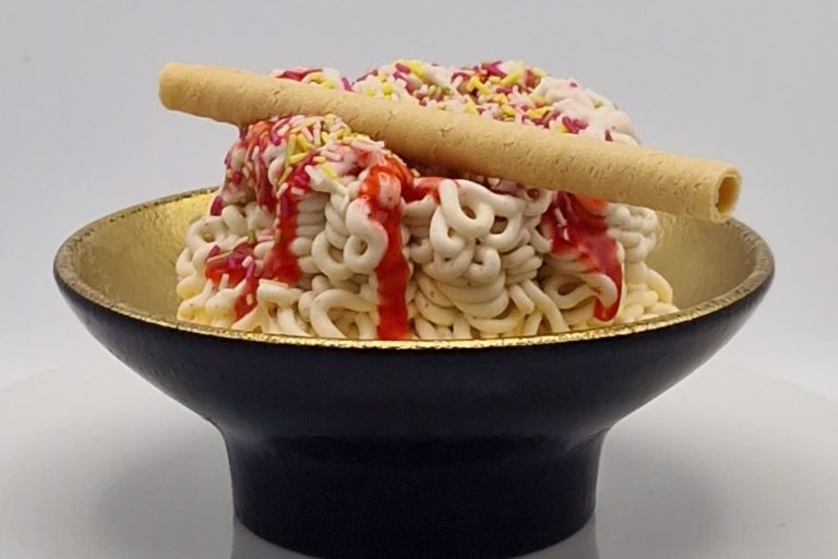 Spaghetti Eis bambini Schüssel mit Spghettieis, Sahne und einer Waffelrolle als Dekoration.