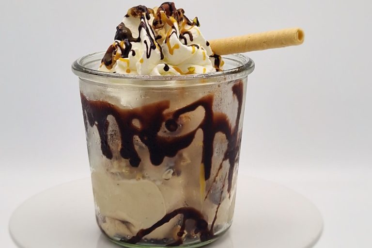 Crunchy nut Eisbecher mit Sahne, Nüssen, Krokant, Schokoladensauce und einer Waffel.